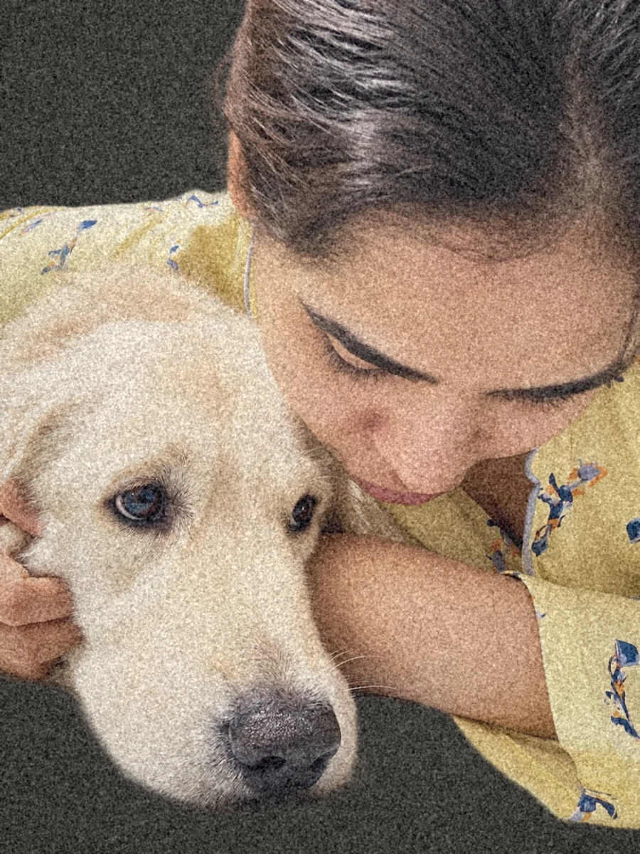 Gayathri hugging her English cream retriever on the bed